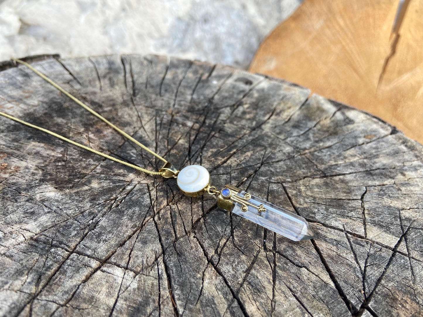 Pendant rock crystal with operculum with spirals, dots and small stone, brass