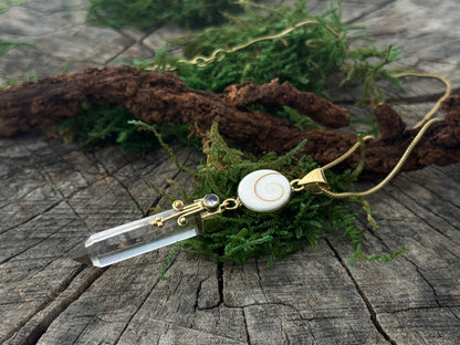 Pendant rock crystal with operculum with spirals, dots and small stone, brass 