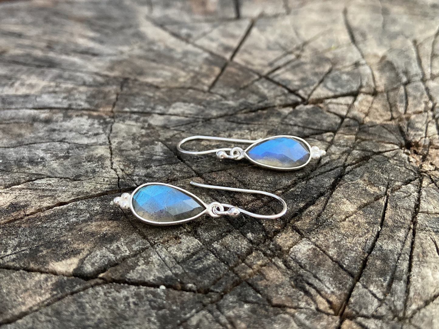 Simple earrings made of silver with faceted labradorite stone in the shape of a teardrop 