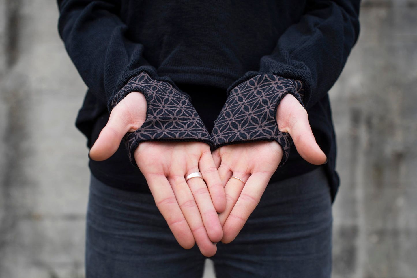 half-length knitted sweater with a patterned hood and thumbholes in black 